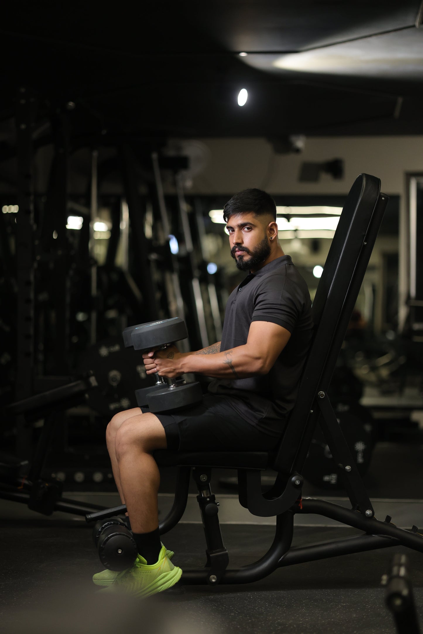 Person exercising with a weight machine in a gym setting in black shorts and drifit t shirt